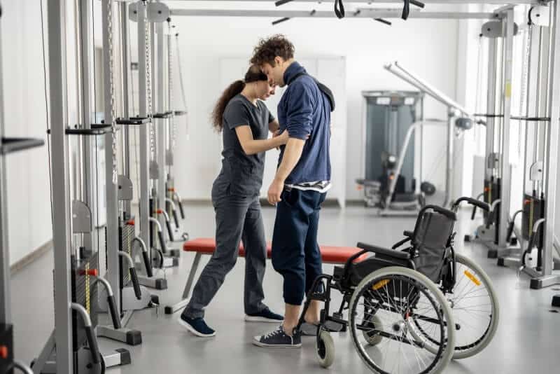 A man and woman in a wheelchair in a gym.